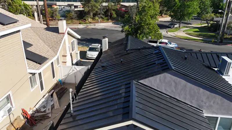 Aerial view down a black standing seam roof ridge with closed hips and trimmed eaves