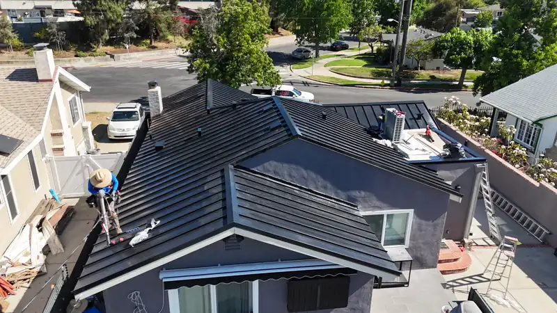 Installer working on a new black standing seam metal roof during a reroof