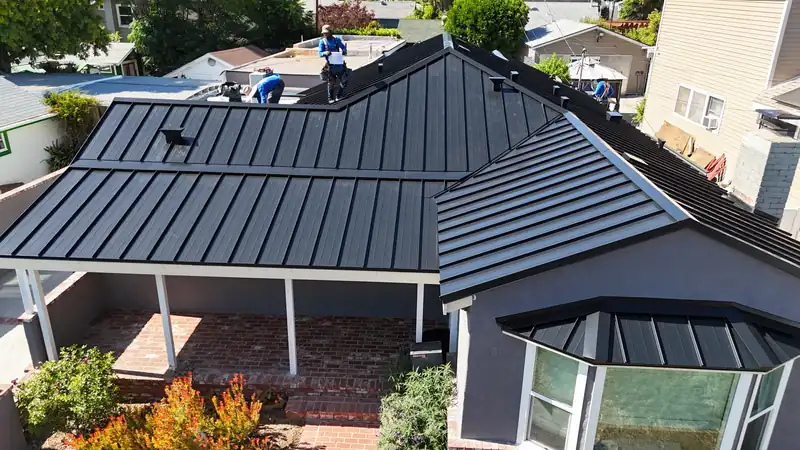 Black standing seam panels meeting at a gable, with roof vents set into the panels